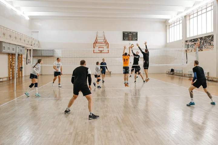 Mecz siatkówki w jasnej hali, gracze przy siatce
